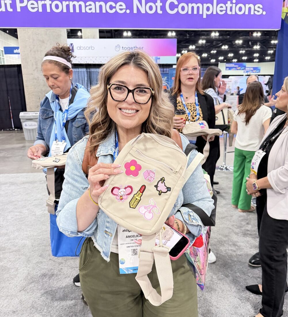 Smiling guest holding up a crossbody bag decorated with her chosen patch letters and motifs at a convention