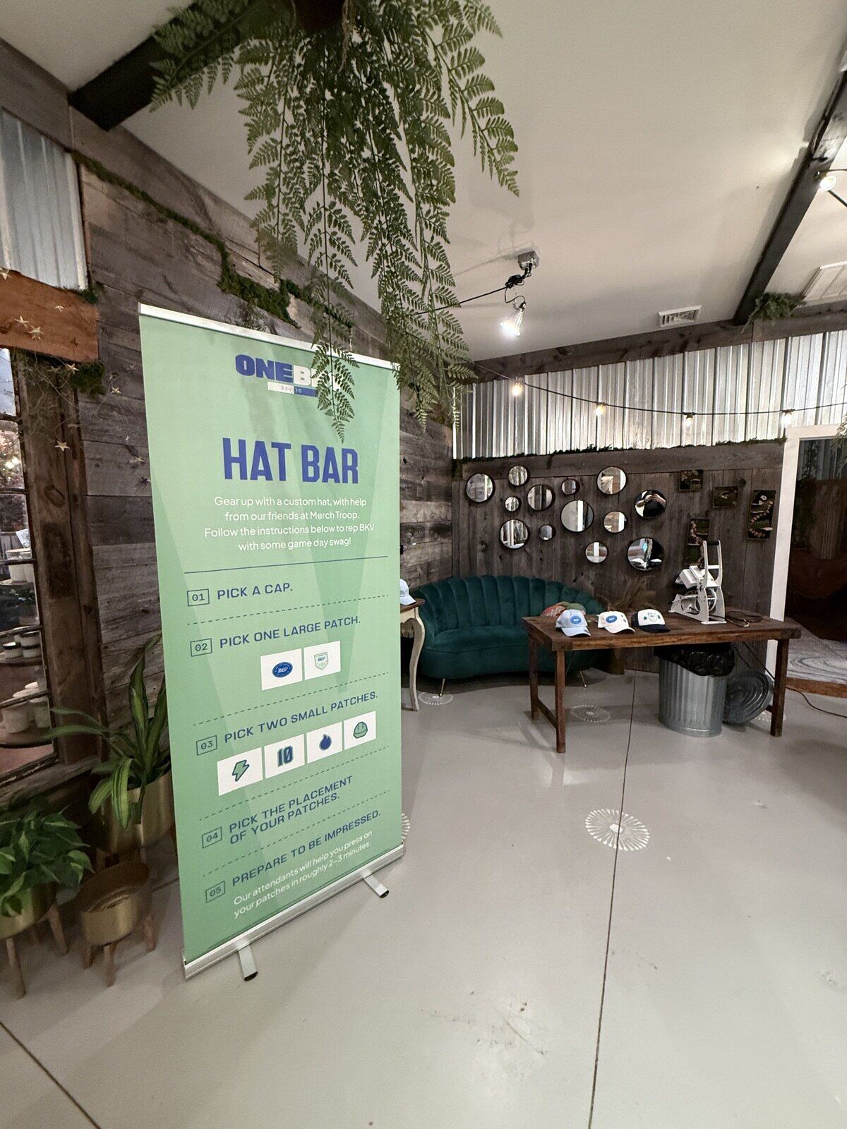 Cozy personalization lounge with a velvet couch, mirror wall, press station, and step-by-step menu banner