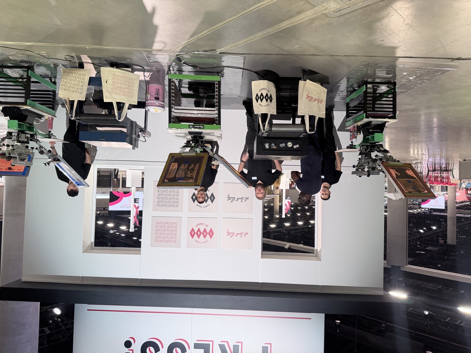 Convention stage with staffed stations and canvas totes finished in flowing script lettering